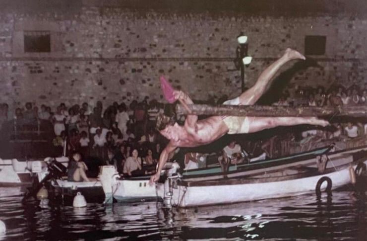 Foto d'archivio in bianco e seppia di un tuffo storico dal palo della cuccagna