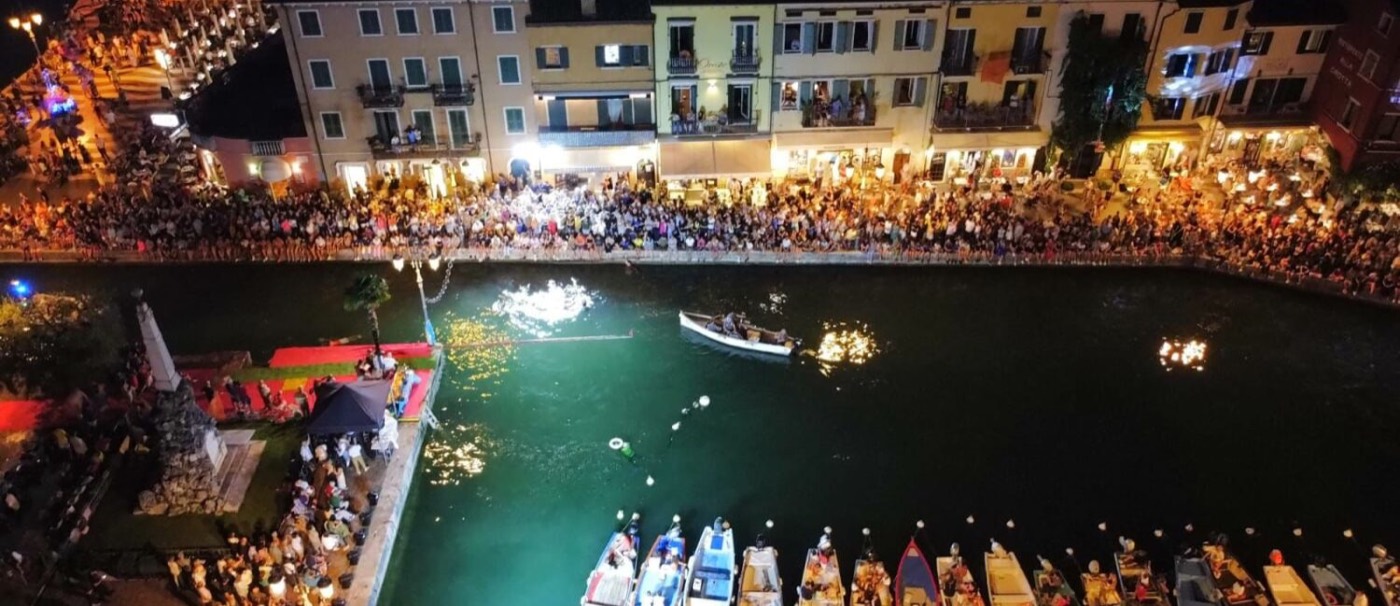 Veduta dall'alto del Porto Vecchio di Lazise gremito di pubblico durante la Cuccagna, di notte