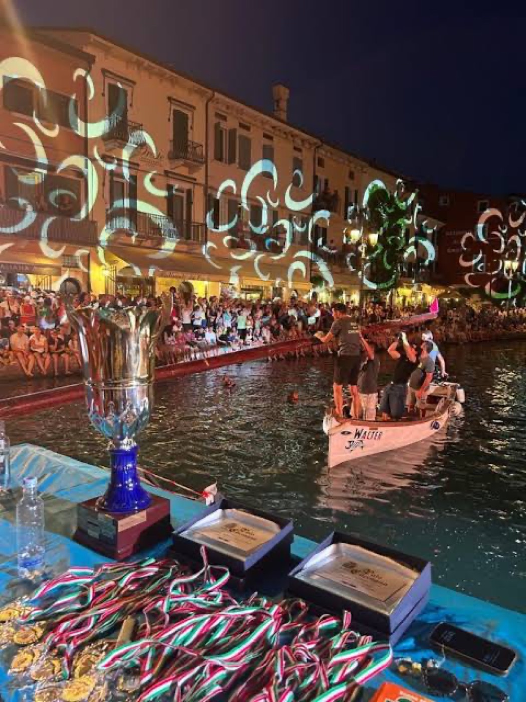 La coppa e le medaglie della Cuccagna del Cadenon esposte, con le proiezioni luminose sul porto di Lazise